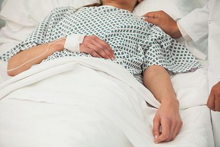 Heath care worker placing a hand on the shoulder of a sick patient in bed.