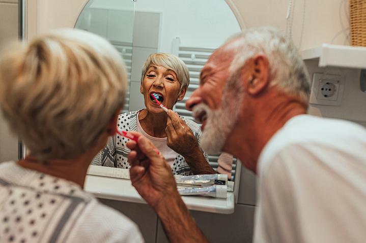 Elderly man brushing wife’s teeth Elderly man brushing wife’s teeth