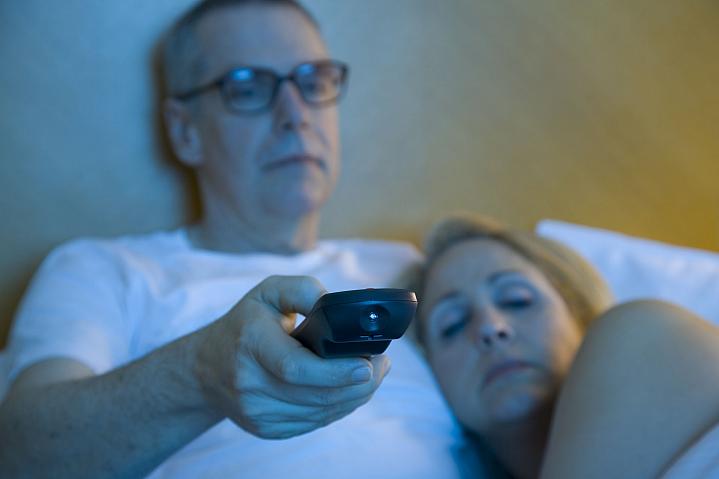 Sleepy couple watching television in bed Sleepy couple watching television in bed