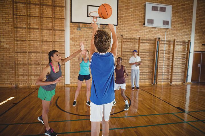 High school kids playing basketball in a gym High school kids playing basketball in a gym