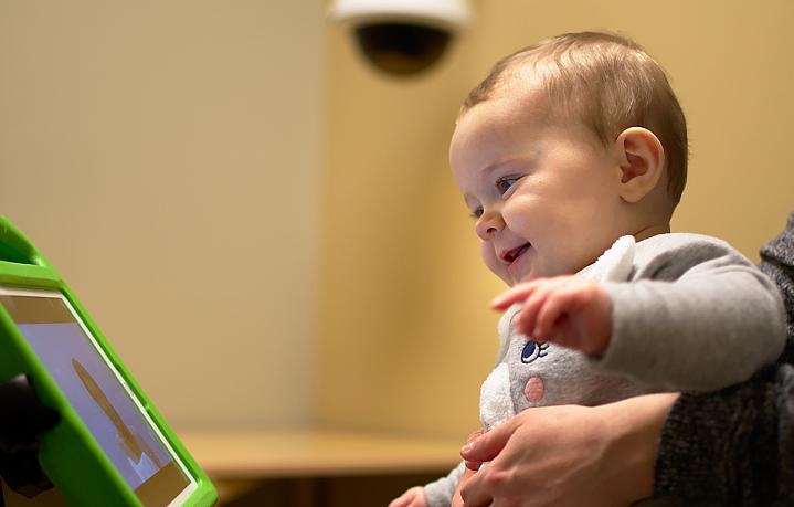 Smiling toddler looking at person on tablet screen Smiling toddler looking at person on tablet screen