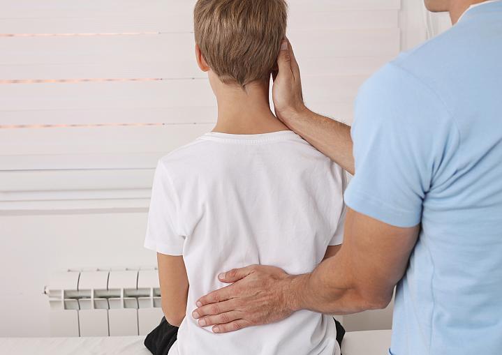 Child getting his back examined by a health care professional