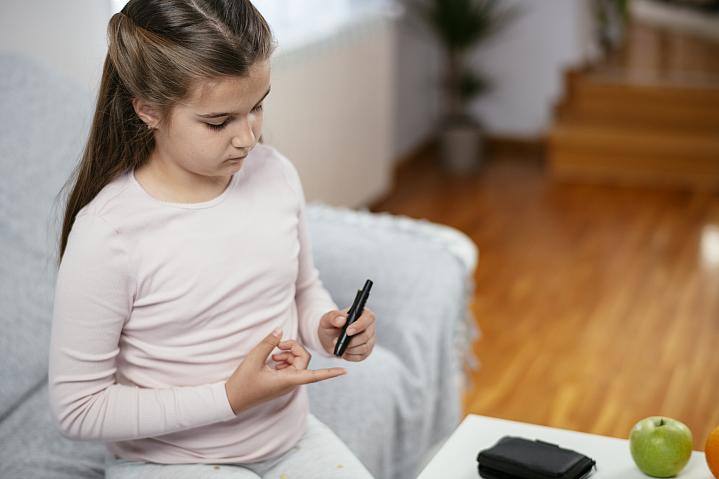 Young girl checking her blood sugar levels