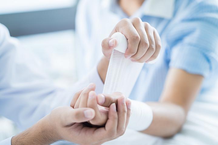 Close up of a doctor bandaging the upper limb on a patient Close up of a doctor bandaging the upper limb on a patient