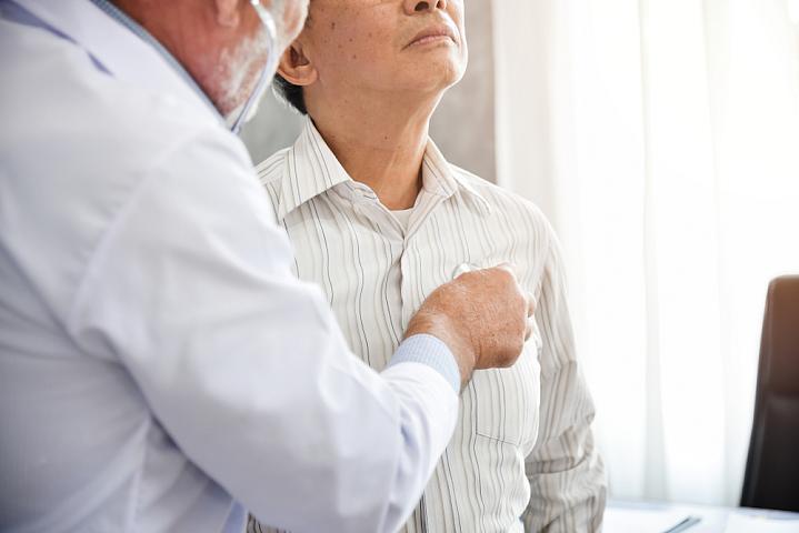 Doctor listening to an older patient's chest with a stethoscope.