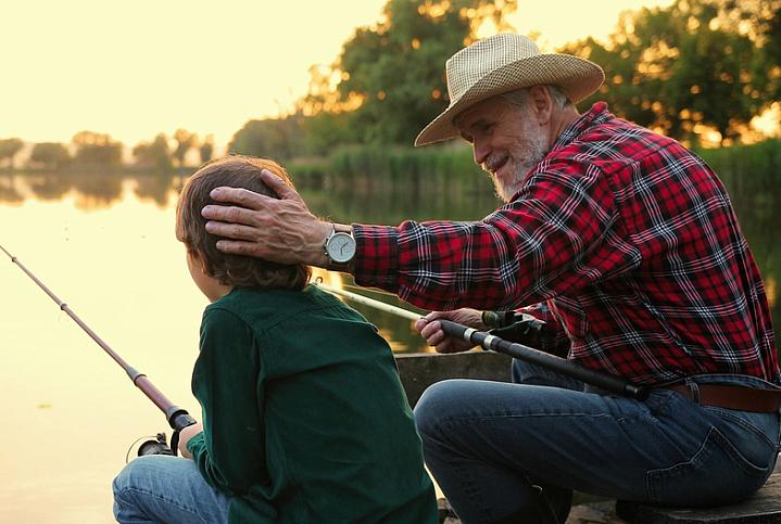 Man chatting with grandson while fishing.