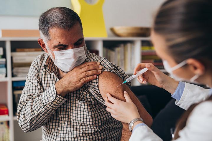 Person wearing a mask getting a COVID-19 vaccine from their health care provider Person wearing a mask getting a COVID-19 vaccine from their health care provider
