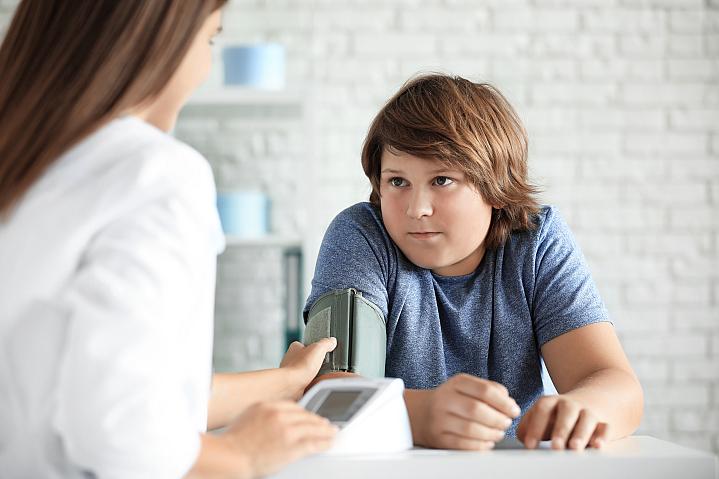Boy who is overweight getting his blood pressure checked by health care professional Boy who is overweight getting his blood pressure checked by health care professional.